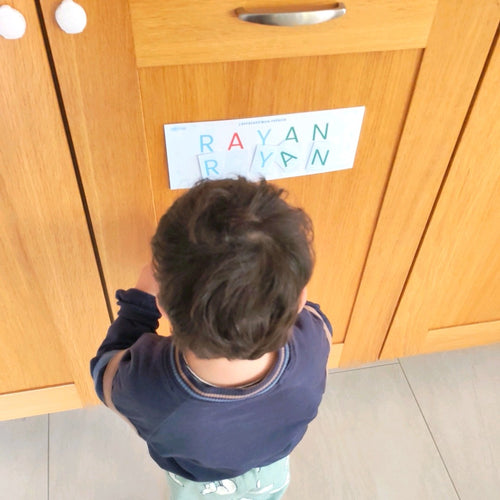Le prénom collé à hauteur d'enfant sur un placard : il replace les lettres de RAYAN sous le modèle
