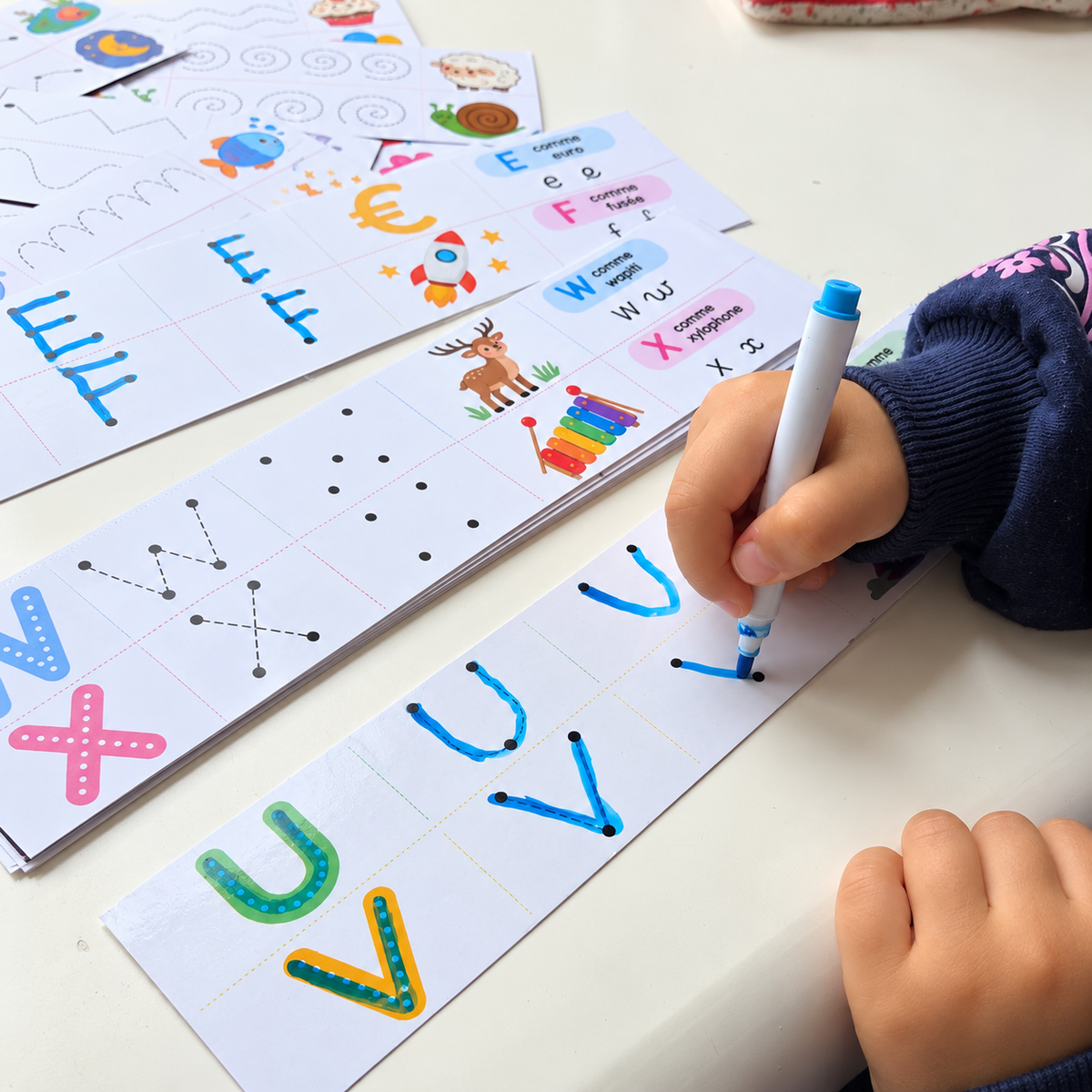 Enfant qui trace les lettres U et V au feutre effaçable sur une bande pelliculée